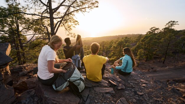 Group of hikers taking a break on a rock at sunset.