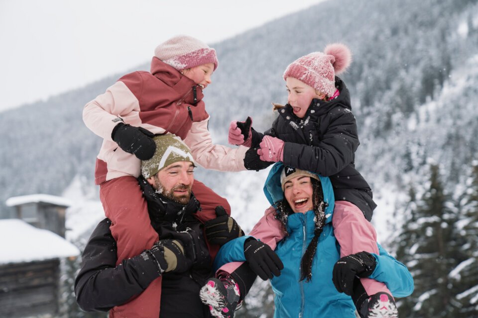 © INTERSPORT International Corporation GmbH Eine Familie hat Spaß im Schnee, wobei die Eltern ihre Kinder Huckepack nehmen. | © INTERSPORT International Corporation GmbH