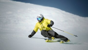 © Fischer Sports GmbH Skifahrer in gelber Jacke fährt eine schneebedeckte Piste hinunter. | © Fischer Sports GmbH
