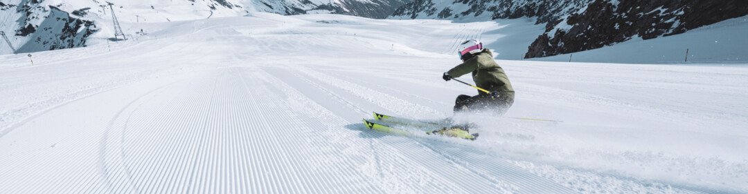 Sciatore su pista battuta in paesaggio montano innevato.