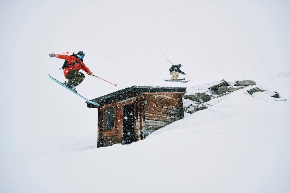 © Fischer Sports GmbH Zwei Skifahrer springen über ein Gebäude im Schnee. | © Fischer Sports GmbH