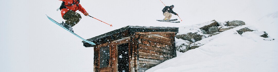 Due sciatori saltano sopra un edificio nella neve. | © Fischer Sports GmbH
