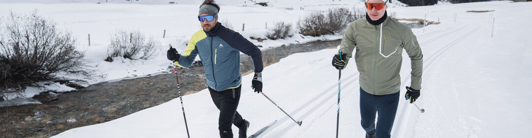 Due uomini fanno sci di fondo in un paesaggio innevato. | © INTERSPORT International Corporation GmbH