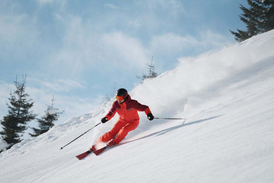 © INTERSPORT International Corporation GmbH Skier in red suit skiing down a snowy slope. | © INTERSPORT International Corporation GmbH