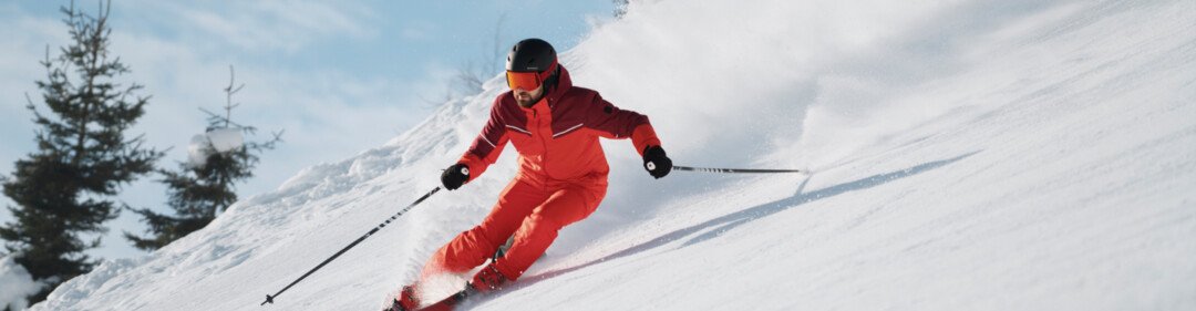 © INTERSPORT International Corporation GmbH Sciatore in tuta rossa che scende una pista innevata. | © INTERSPORT International Corporation GmbH