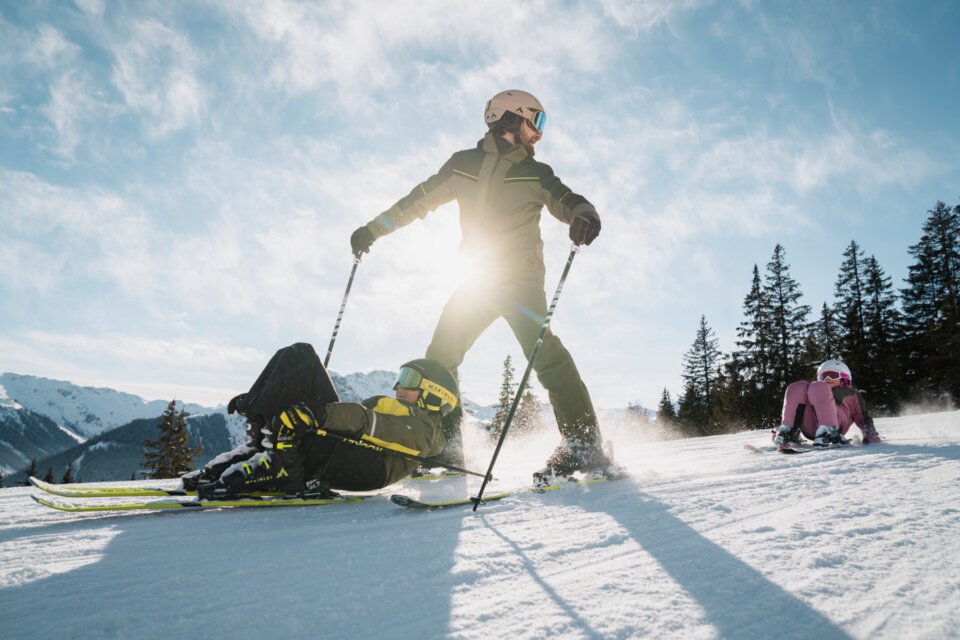 © INTERSPORT International Corporation GmbH Skifahrer stürzt und wird von anderem Skifahrer überquert, während ein Kind im Hintergrund sitzt. | © INTERSPORT International Corporation GmbH