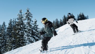 Due snowboarder su una pista innevata