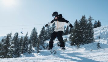 © INTERSPORT International Corporation GmbH Snowboarder springt in der Luft vor verschneitem Hintergrund. | © INTERSPORT International Corporation GmbH