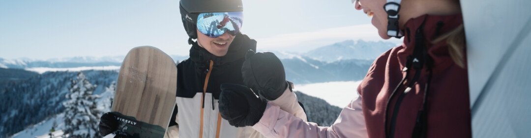 © INTERSPORT International Corporation GmbH Due snowboarder si stringono la mano sulla neve. | © INTERSPORT International Corporation GmbH