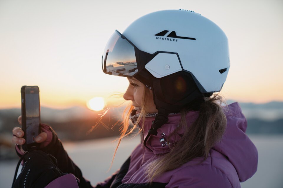 © INTERSPORT International Corporation GmbH Woman with ski helmet filming sunrise with phone | © INTERSPORT International Corporation GmbH