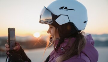 © INTERSPORT International Corporation GmbH Woman with ski helmet filming sunrise with phone | © INTERSPORT International Corporation GmbH