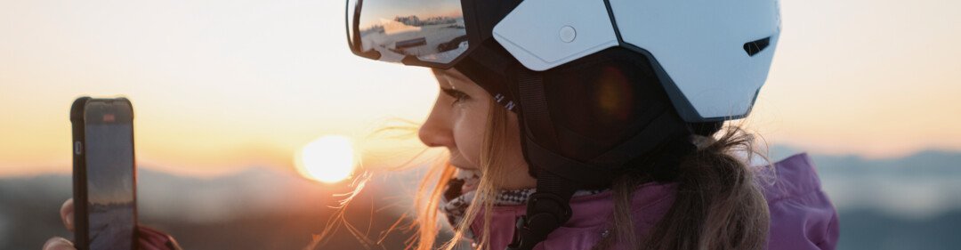 © INTERSPORT International Corporation GmbH Donna con casco da sci che filma l'alba con il telefono | © INTERSPORT International Corporation GmbH