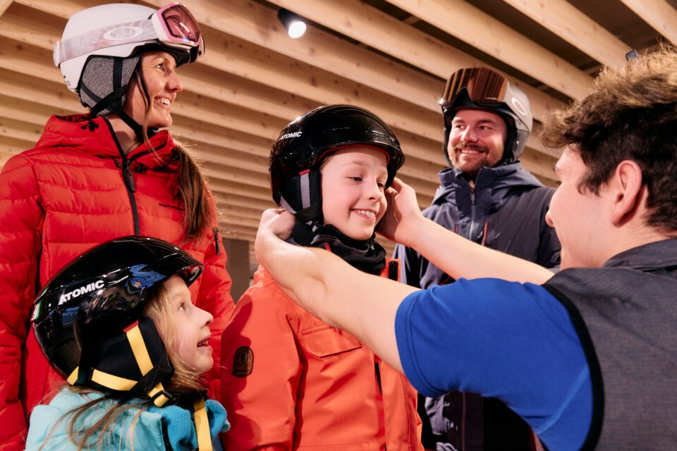 © ARMIN WALCHER Family trying on ski helmets in a shop. | © ARMIN WALCHER