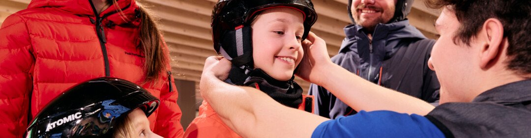© ARMIN WALCHER Famiglia che prova caschi da sci in un negozio. | © ARMIN WALCHER