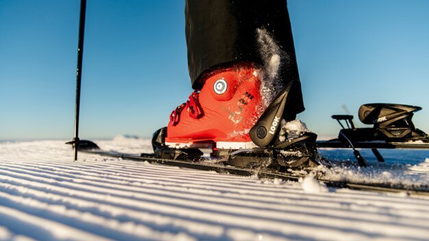 Roter Skischuh in Bindung auf präparierter Piste | © ROSSIGNOL