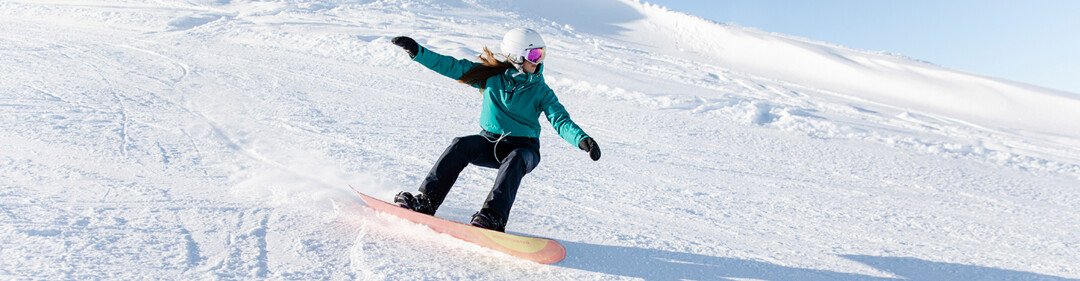Snowboarderin fährt einen schneebedeckten Hang hinunter. | © Rossignol