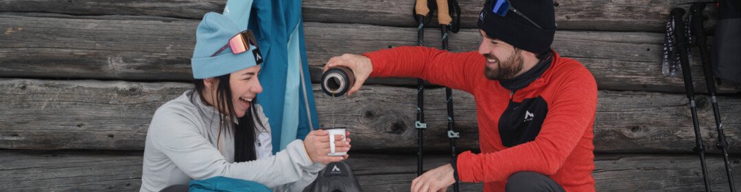 Due persone si prendono una pausa dalle ciaspolate, bevendo caffè. | © INTERSPORT International Corporation GmbH