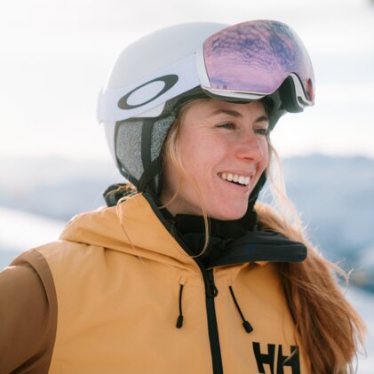 Frau mit Skihelm und Skibrille lächelt.