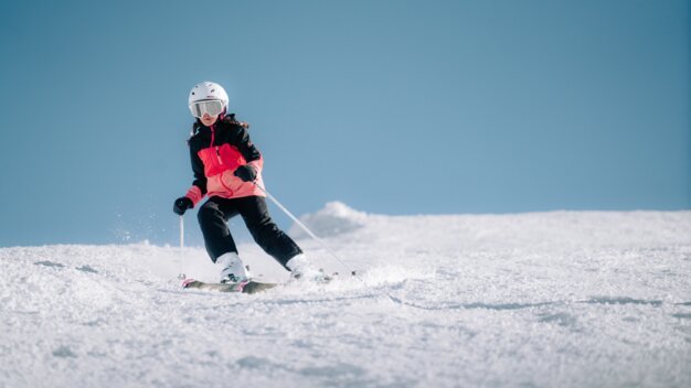 Kind fährt Ski auf einer schneebedeckten Piste.