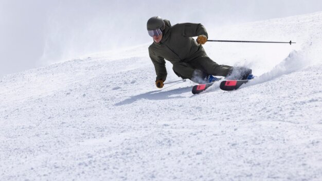 Skifahrer fährt einen schneebedeckten Hang hinunter.