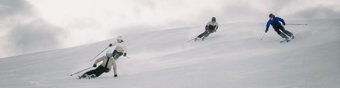 Vier Skifahrer auf einer schneebedeckten Piste