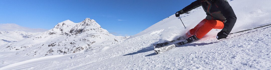 Sciatore che scia su un pendio innevato.