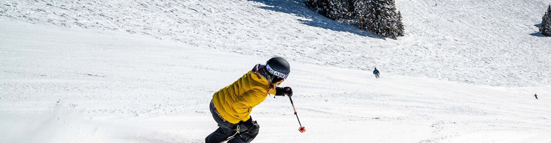 Scattatore con giacca gialla che scia su una pista innevata