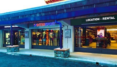 Vista esterna di un negozio Intersport e un negozio di noleggio sci.