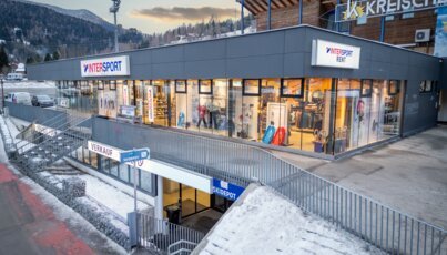 INTERSPORT Rent shop building at a base station with large display windows and access via an outdoor staircase
